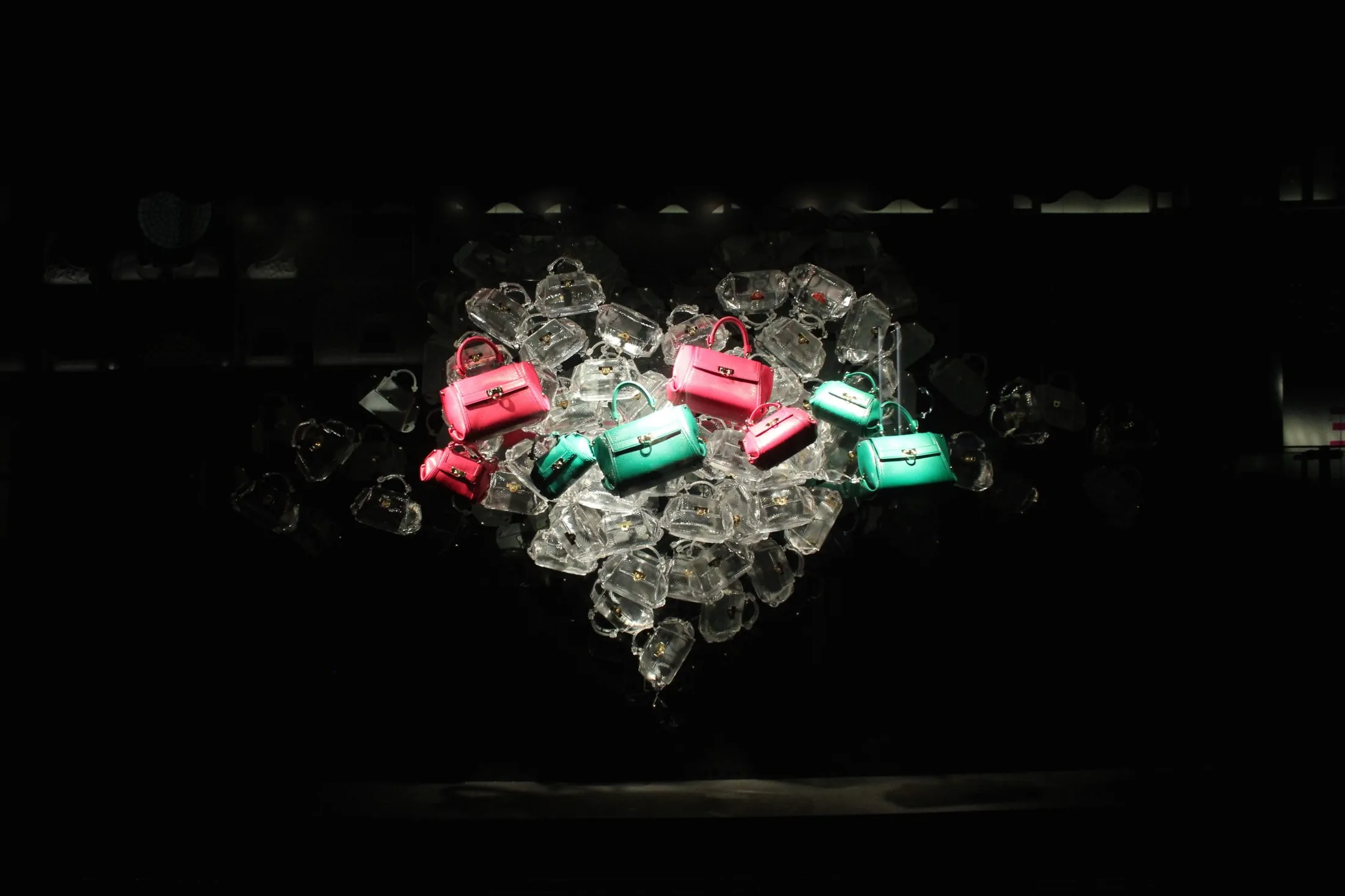 Cuore luminoso composto da elementi trasparenti e borse colorate su fondo nero