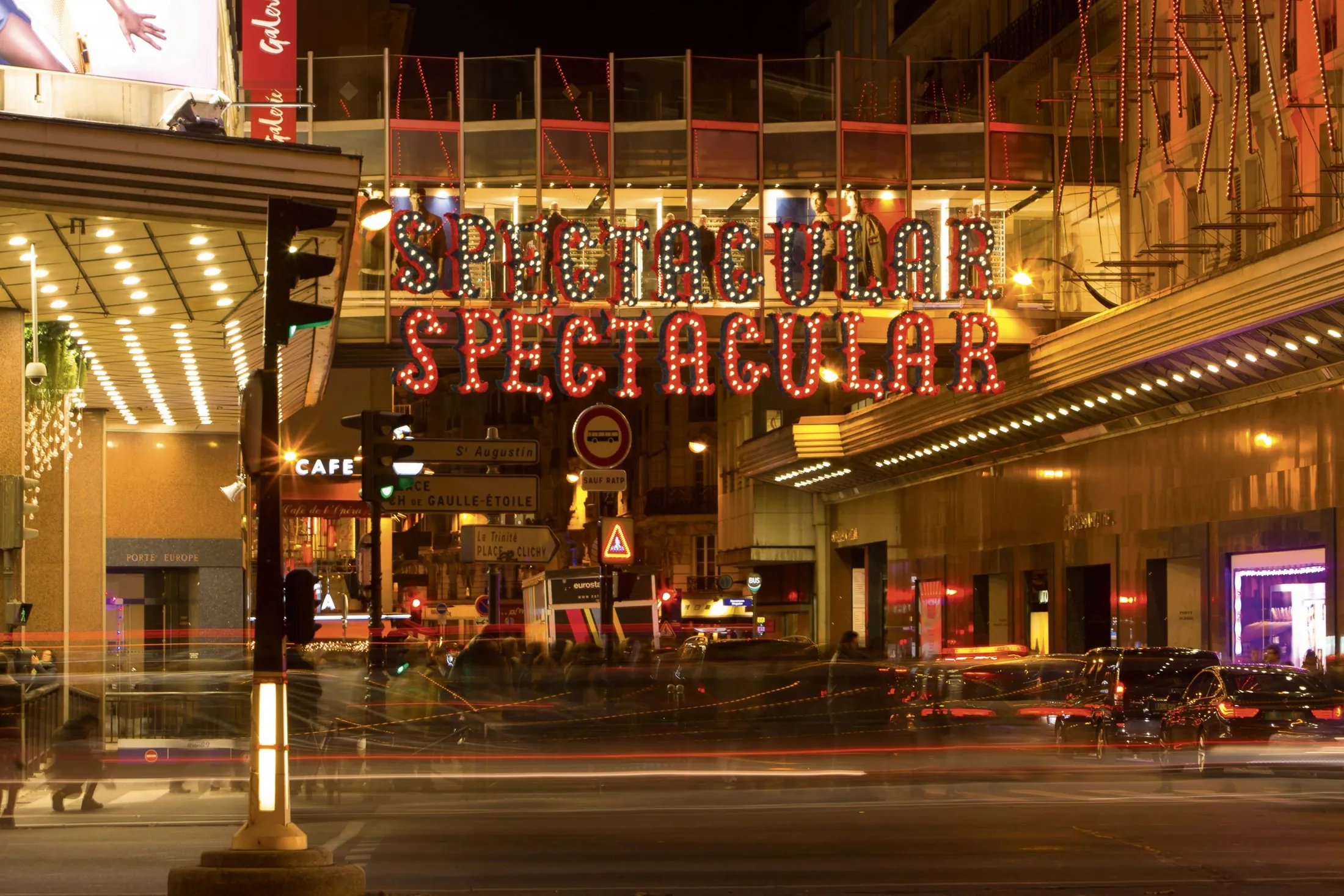 Scritta luminosa rossa e dorata sopra l'ingresso di una galleria commerciale illuminata di notte